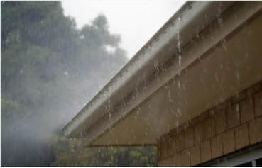 Torrential rain pours down and trickles off a gutter