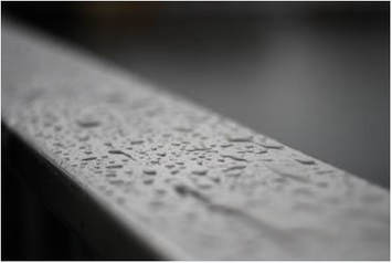 A close up of rain droplets on a metal gutter